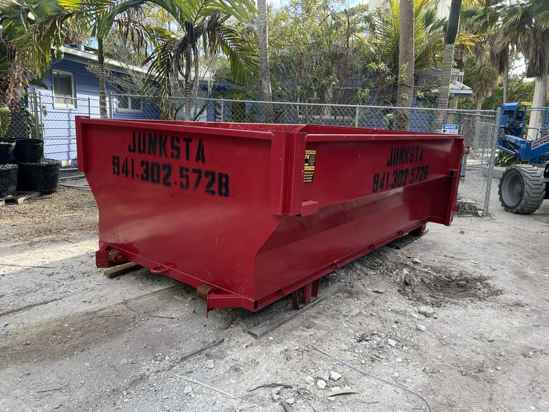 Red Junksta roll-off dumpster on a Manatee County job site