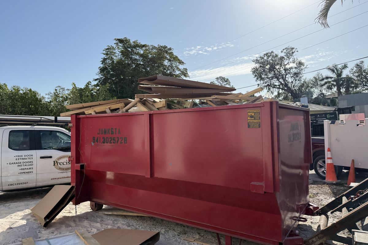 Red Junksta roll-off dumpster delivered in Holmes Beach, FL