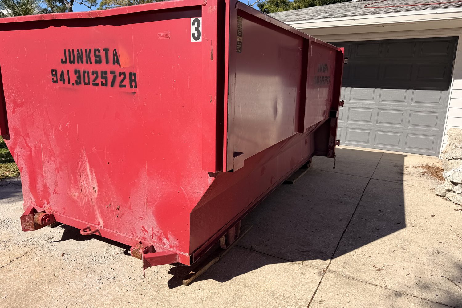 Red Junksta roll-off dumpster delivered on a Bradenton driveway